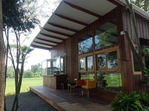 Casa con ventanas grandes y terraza de madera. en Baan Tonjaeng Resort en Chai Nat