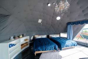 a bedroom with a bed with blue sheets and a chandelier at HIKARI DOME - Vacation STAY 49575v in Teruma