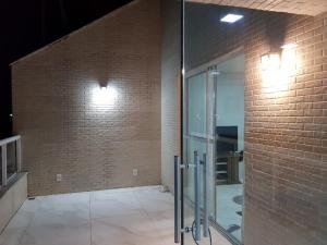 um quarto com uma porta de vidro numa parede de tijolos em Jockey Family Chamonix 2 em Vila Velha