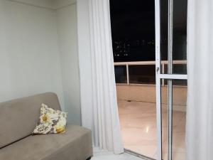ein Wohnzimmer mit Sofa und Blick auf einen Balkon in der Unterkunft Jockey Family Chamonix 2 in Vila Velha