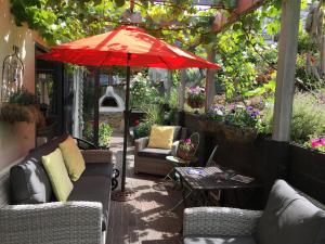 a patio with couches and a red umbrella at Tempest on Wanaka in Wanaka