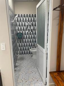 baño con aseo y puerta de ducha de cristal en Nhà khách 369 en Cà Mau