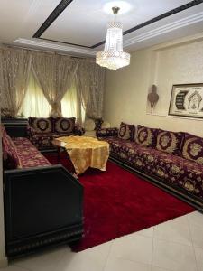een woonkamer met een bank en een rood tapijt bij Ryad zitoune in Meknès