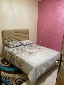 een slaapkamer met een bed en een roze muur bij Ryad zitoune in Meknès