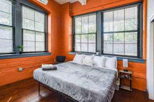 een slaapkamer met een bed met oranje muren en ramen bij NY Style Centric Loft with King Bed by Park av in Rochester
