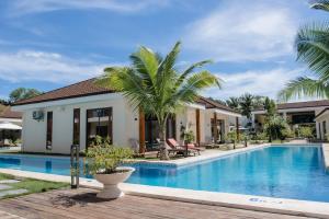 a villa with a swimming pool and palm trees at Amphitrite Resort in Panglao