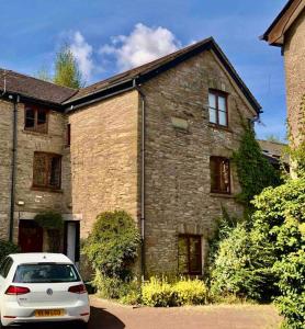 Hay On Wye Welsh Townhouse in Hay centre في هاي-أون-واي: سيارة بيضاء متوقفة أمام منزل من الطوب