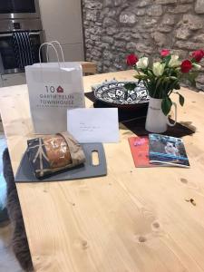 a wooden table with a plate of food and flowers at Hay On Wye Welsh Townhouse in Hay centre in Hay-on-Wye