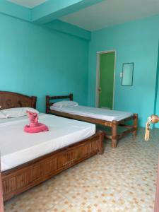Medano Sunset Resort في مامباجاو: سريرين في غرفة بجدران زرقاء