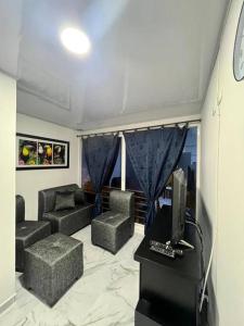 ein Wohnzimmer mit einem TV, einem Sofa und Stühlen in der Unterkunft Comodo Apartamento Cartago Valle in Cartago