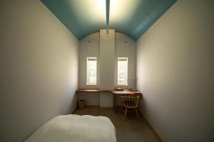ein kleines Zimmer mit einem Bett, einem Tisch und einem Fenster in der Unterkunft Megurimegurasu in Goto