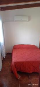 Una cama roja en una habitación con una pared blanca en Apto. en Colonia, a 1 cuadra de la Plaza de Toros en Colonia del Sacramento