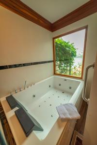 a bathroom with a large bath tub with a window at Riosol Hotel Laguna Azul in Sauce