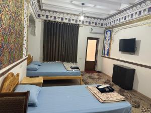 a room with two beds and a flat screen tv at TEMUR Hotel in Bukhara