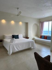 a bedroom with a white bed with a view of the ocean at Hotel Estrella de Mar in Zipolite