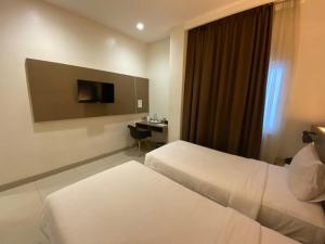 una camera d'albergo con 2 letti e una scrivania di OPI Indah Hotel a Palembang