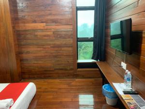 - une chambre avec des murs en bois, une fenêtre et un lit dans l'établissement Musse Hotel @Slim River, à Slim River