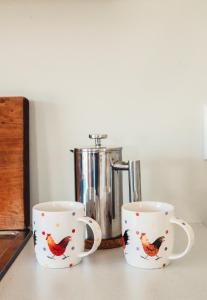 Duas canecas de café com um desenho de galo. em The Hen House em Kaipara Flats
