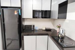 a kitchen with white cabinets and a black refrigerator at Equine Park Landed H.stay-Farm in the City-12Pax in Seri Kembangan