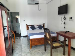 a bedroom with a bed and a desk and a chair at Hotel Sun Blue in Trincomalee