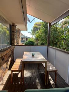 a wooden table and benches on a balcony with windows at Lennox Beach Oasis 3 Bedrooms in town in Lennox Head