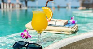 a glass of orange juice next to a swimming pool at Sara Resort in Koh Rong Sanloem