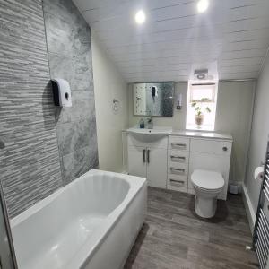 a bathroom with a tub and a toilet and a sink at Ulverston Town Centre Flat (2 Bedrooms) in Ulverston