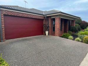 a red garage door on a brick house at Mid Coast Stayz in Waurn Ponds