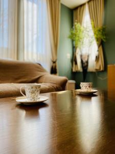 dos tazas y platillos sentados en una mesa de madera en 民泊なべやさんち, en Nanae