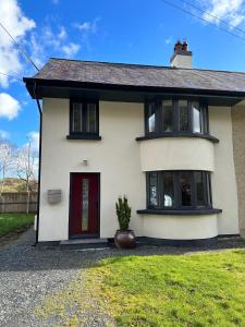 uma casa branca com uma porta vermelha em Dolwen Snowdonia Home by PolkaDot em Caernarfon