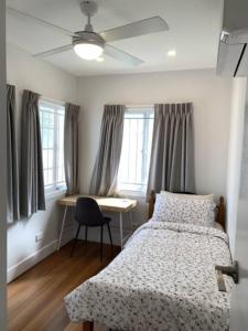 a bedroom with a bed and a desk and windows at Fully Renovated 3 Bedroom House in Belmont