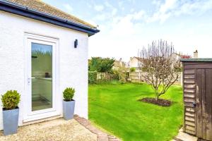 a white house with a door and a green yard at Beautiful Bungalow near to Beach in Selsey