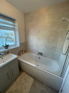 a bathroom with a shower and a tub and a sink at Beautiful Bungalow near to Beach in Selsey