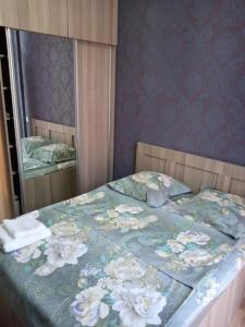 a bed with a blue blanket with flowers on it at Marine's flat in Tbilisi City