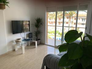a living room with a couch and a tv at Acogedor apartamento con piscina en Vilafortuny, Cambrils in Cambrils
