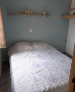 ein weißes Bett in einem Zimmer mit Regal in der Unterkunft Mobilhome 4 pers La palmyre in Les Mathes