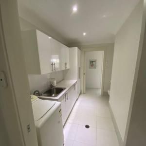 uma cozinha com armários brancos, um lavatório e uma casa de banho em Worrigee Retreat Guesthouse em Worragee