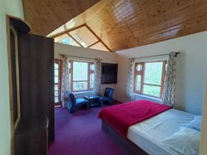 a bedroom with a bed and a desk and windows at Shepherd Inn the Hill in Nagar