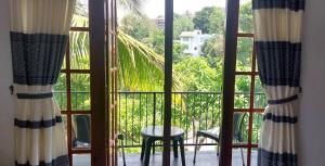 ein offenes Fenster mit Blick auf eine Palme in der Unterkunft The Comfort in Kandy