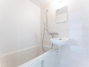 a white bathroom with a sink and a shower at Tabist Tatebayashi Station Hotel in Tatebayashi