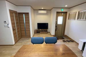 a living room with two blue chairs and a television at 富士山下Cottage-B in Narusawa