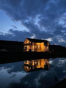 een huis met zijn reflectie in het water 's nachts bij Cabana Rustic Sancel 