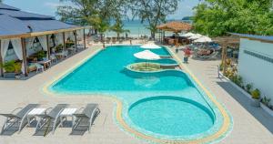 a swimming pool with chairs and umbrellas next to the beach at Sara Resort in Koh Rong Sanloem