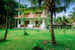 a house in the middle of a yard with palm trees at River Cottage in Wellawaya