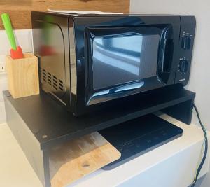 a microwave sitting on top of a black shelf at SYA Hotel-祇園 in Fukuoka