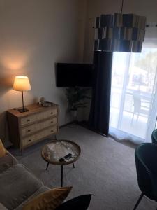ein Wohnzimmer mit einem Sofa, einem Tisch und einem TV in der Unterkunft Artemis Apartments in Diakopto