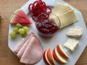 a plate of food with cheese fruit and a bowl of jam at Motel Rovli in Skærbæk