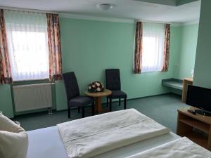 1 Schlafzimmer mit einem Bett, 2 Stühlen und einem Tisch in der Unterkunft Hotel Thannhof in Schweitenkirchen