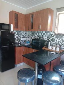 a kitchen with a black refrigerator and some bar stools at SONHOS dreams Self catering Garden Cottages in Bloemfontein
