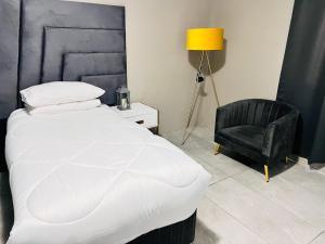a bedroom with a white bed and a black chair at Signature Boutique Guesthouse in Maun